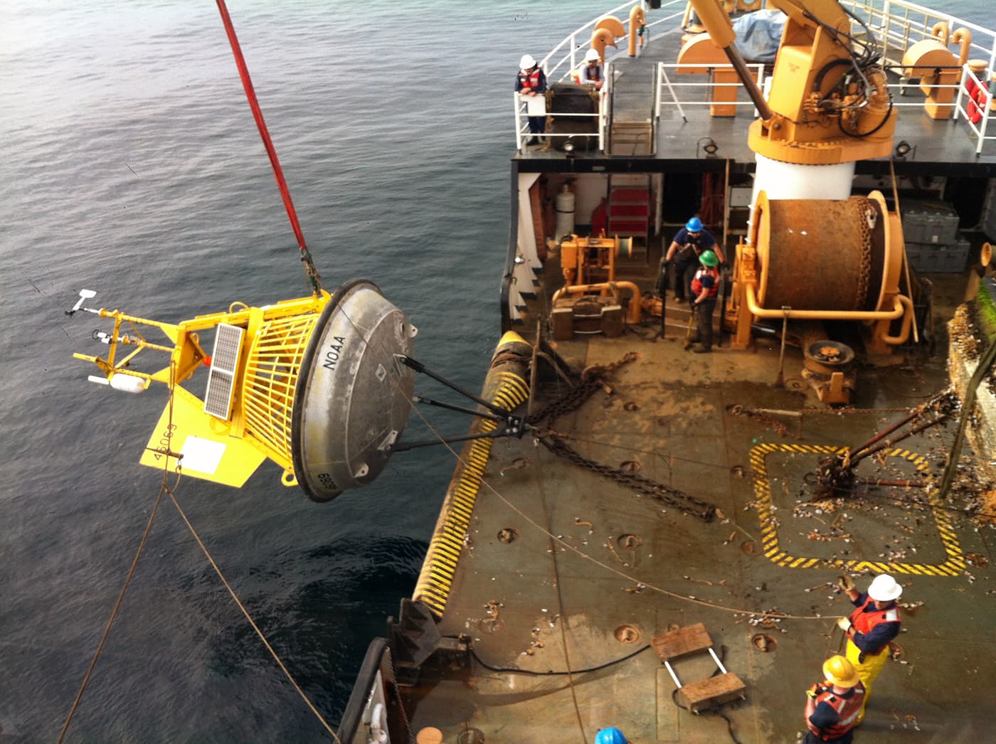 U.S. Coast Guard crew and NOAA technicians repairing a weather buoy at sea